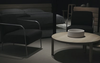 dimly lit bedroom with a coffee table and chairs in the foreground